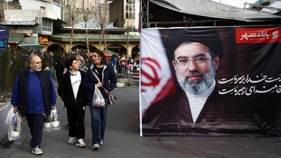 People walk next to a banner with a picture of Iran’s new Supreme Leader, Mojtaba Khamenei, at Tajrish Bazaar, ahead of Nowruz, the Iranian New Year, amid the US-Israeli conflict with Iran, in Tehran on March 19, 2026. (Photo: Majid Asgaripour/WANA via Reuters)