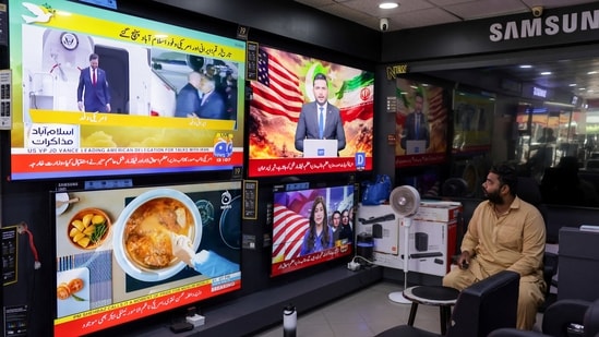A man sits next to televisions at a shop in Karachi showing news regarding the peace talks to be held in Islamabad by delegations from the United States and Iran on April 11, 2026. (Insiya Syed/Reuters Photo)