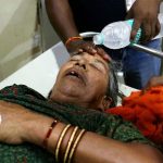 A hospital staff member pours water on the face of a patient suffering from heat stroke at a government hospital during a severe heatwave.