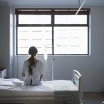 Patient sitting on hospital bed waiting for surgery looking out window