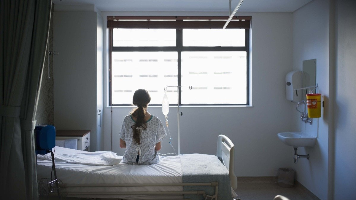 Patient sitting on hospital bed waiting for surgery looking out window
